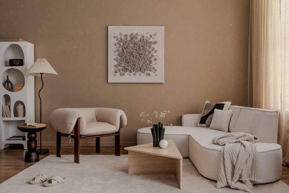 Beige living room with sofa, chair, and art on a tan wall.
