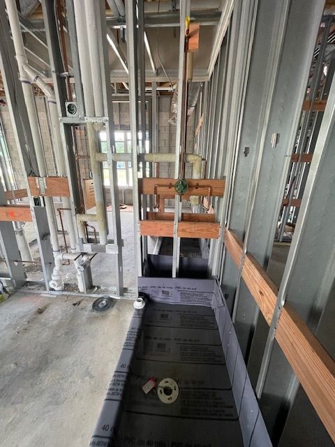 Construction site with metal framing, plumbing, and a shower base.