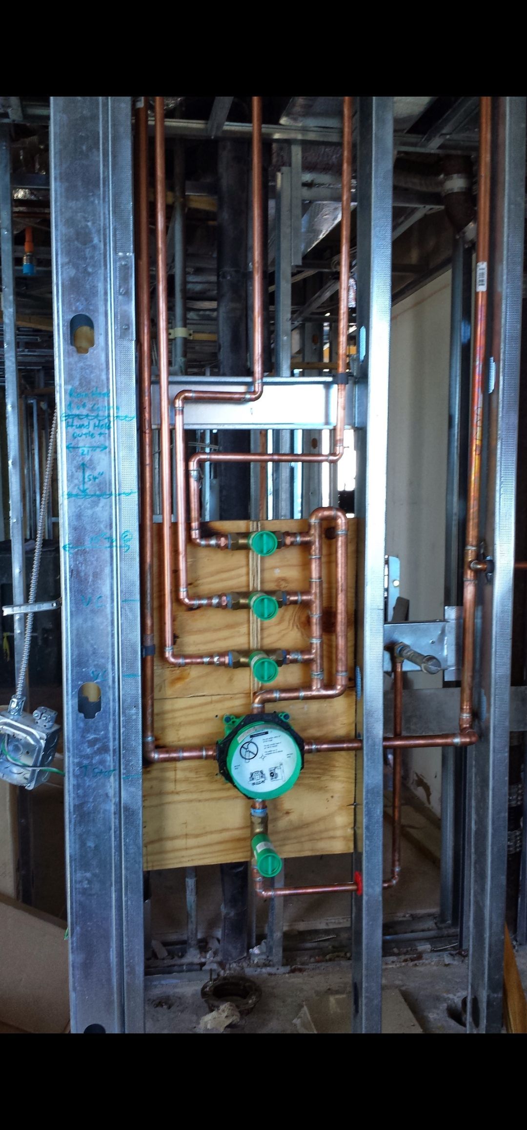 Copper plumbing pipes installed within a metal frame wall. A shower control unit is installed.