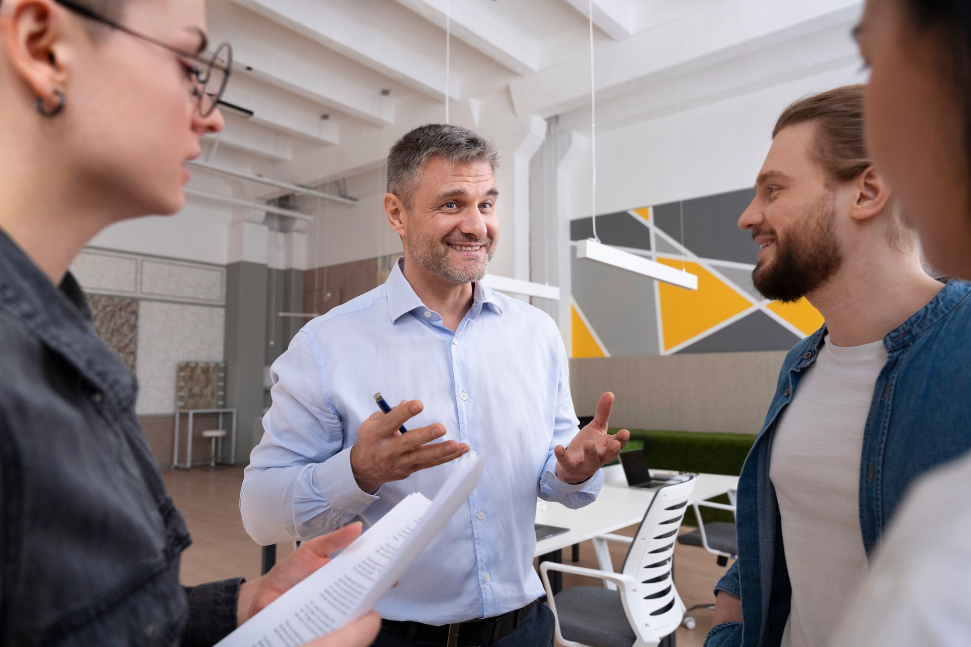 A smiling, confident business leader in a light blue shirt gesturing during a positive discussion with colleagues, representing the successful achievement of financial KPIs and premium returns within a group captive.