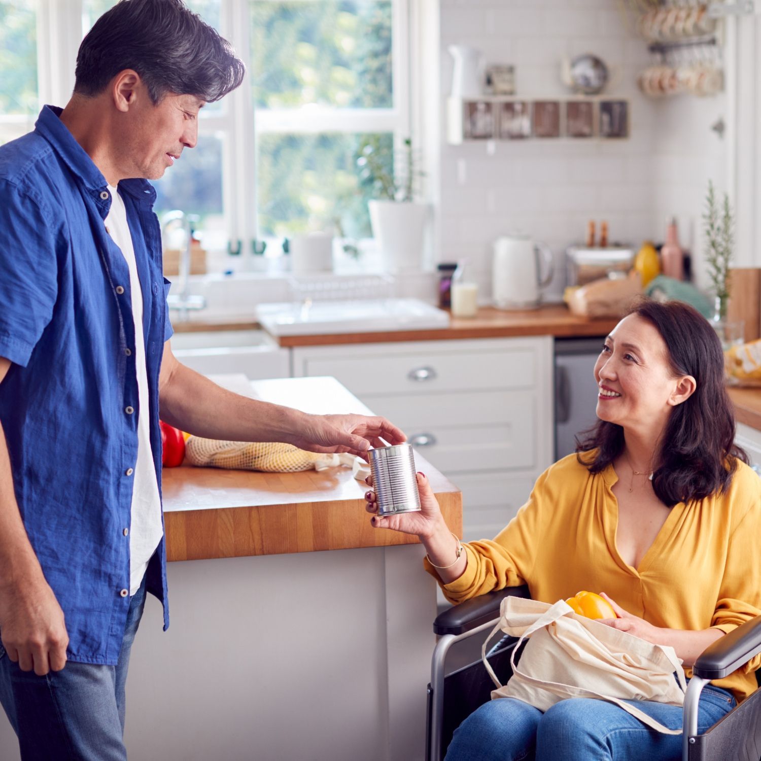 Man hading a drink to a woman in wheelchair
