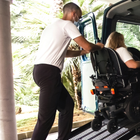 Man pushing wheelchair with a woman sitting on it, to a van