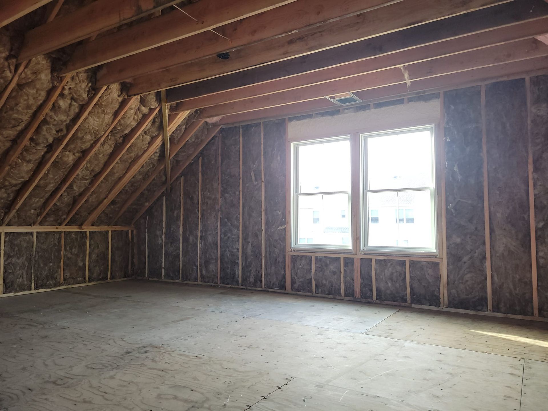 An empty room with two windows and a wooden ceiling