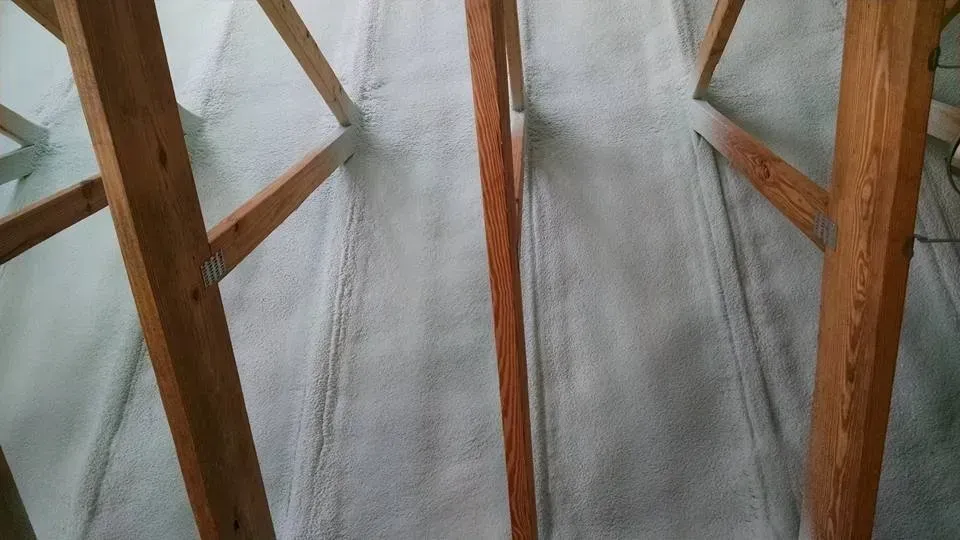 A close up of a wooden structure with a white tarp on the floor.