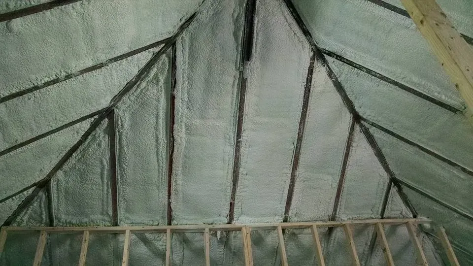 The ceiling of an attic is insulated with spray foam.