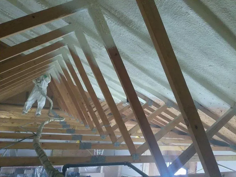 A man is spraying foam on the ceiling of a building