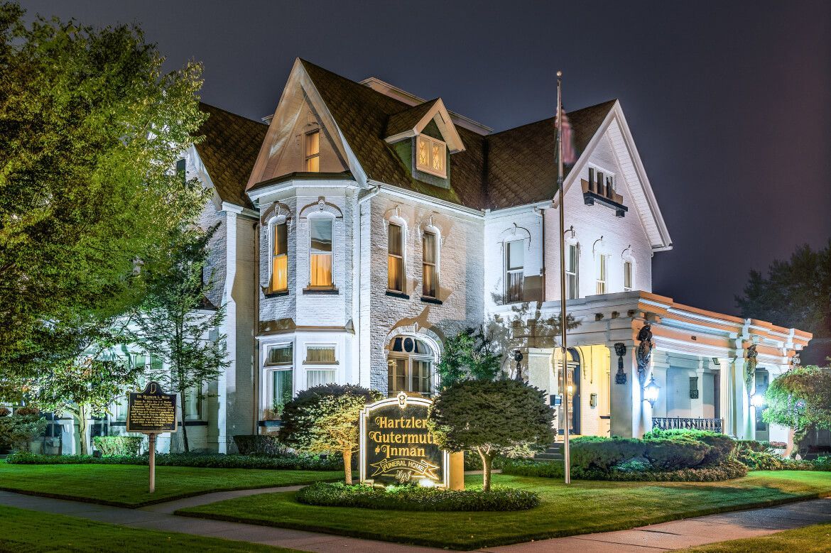 Illuminated historic white house at night with a lit sign and manicured lawn
