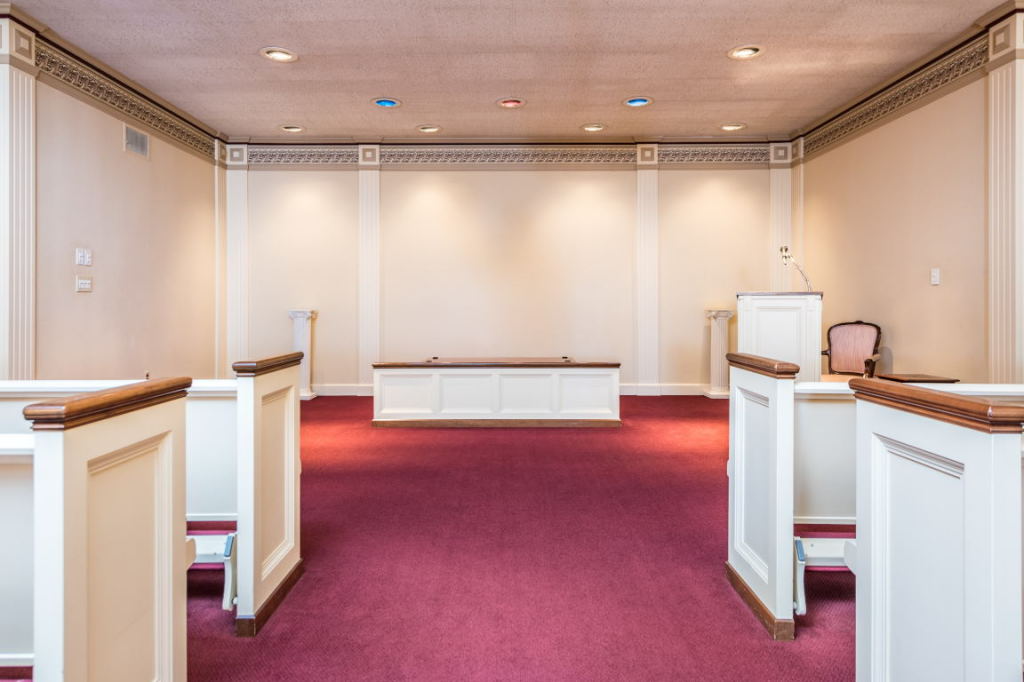 Empty wedding chapel with white pews and red carpet aisle