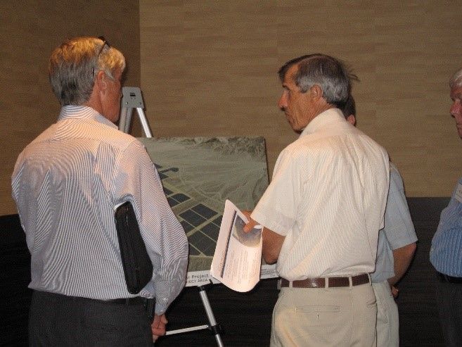 Two men viewing a display board and talking indoors