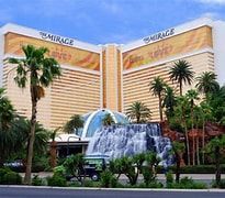The Mirage hotel with a cascading waterfall fountain and palm trees in front
