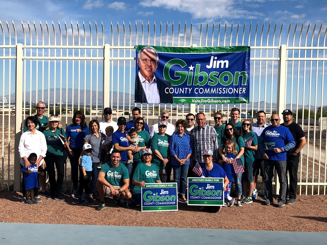 Group posed outdoors with Jim Clyburn campaign banner and signs in front of a white fence.