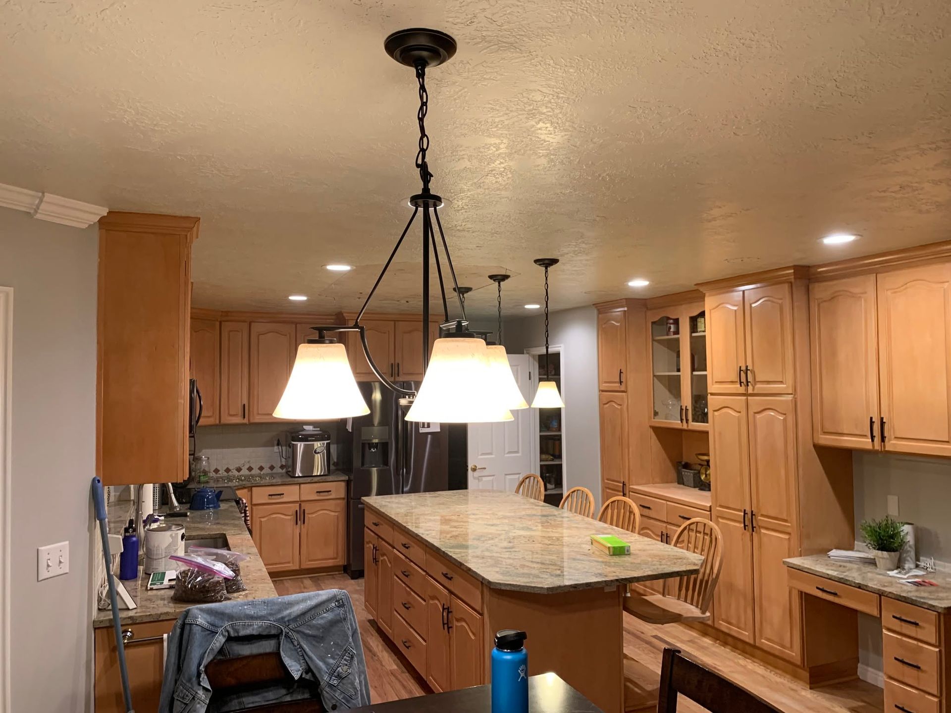 Spacious kitchen with wood cabinets, granite island, and pendant lights hanging over the center.