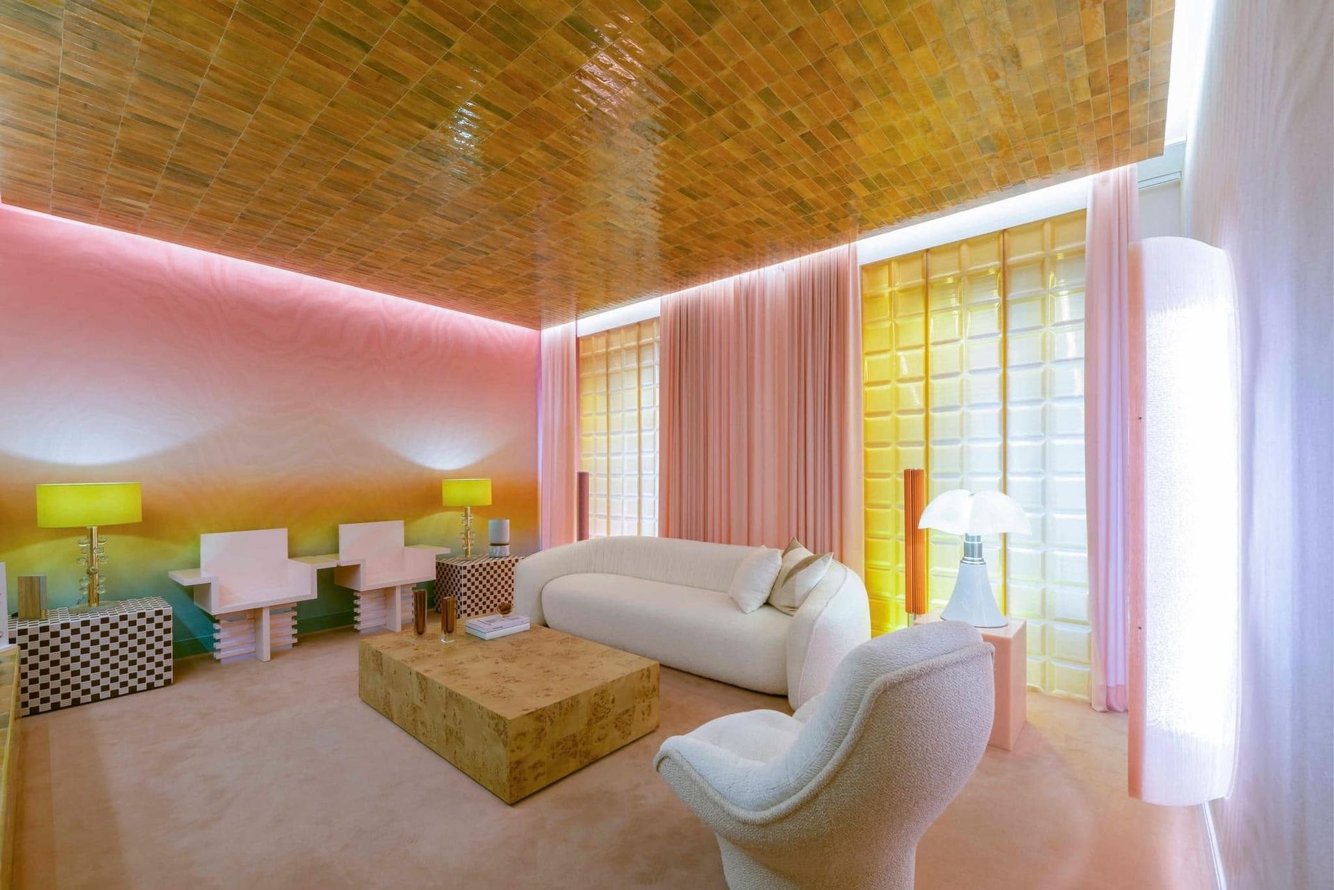 Bright modern living room with white sofa, armchairs, pink walls, wooden ceiling, and large windows