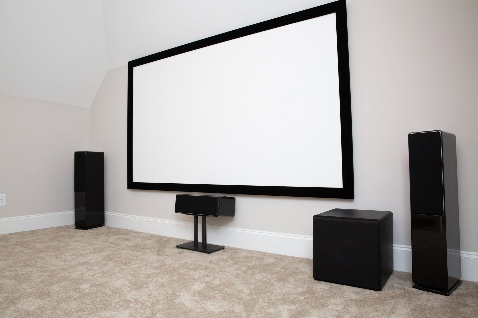 Home theater room with large projection screen and black speakers on carpeted floor