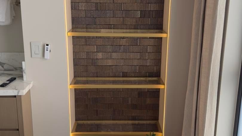Built-in bookshelf with warm LED strip lighting in a doorway alcove