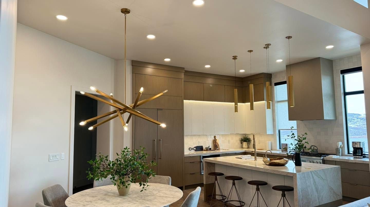 Modern open-plan kitchen and dining area with pendant lights, white island, and large windows
