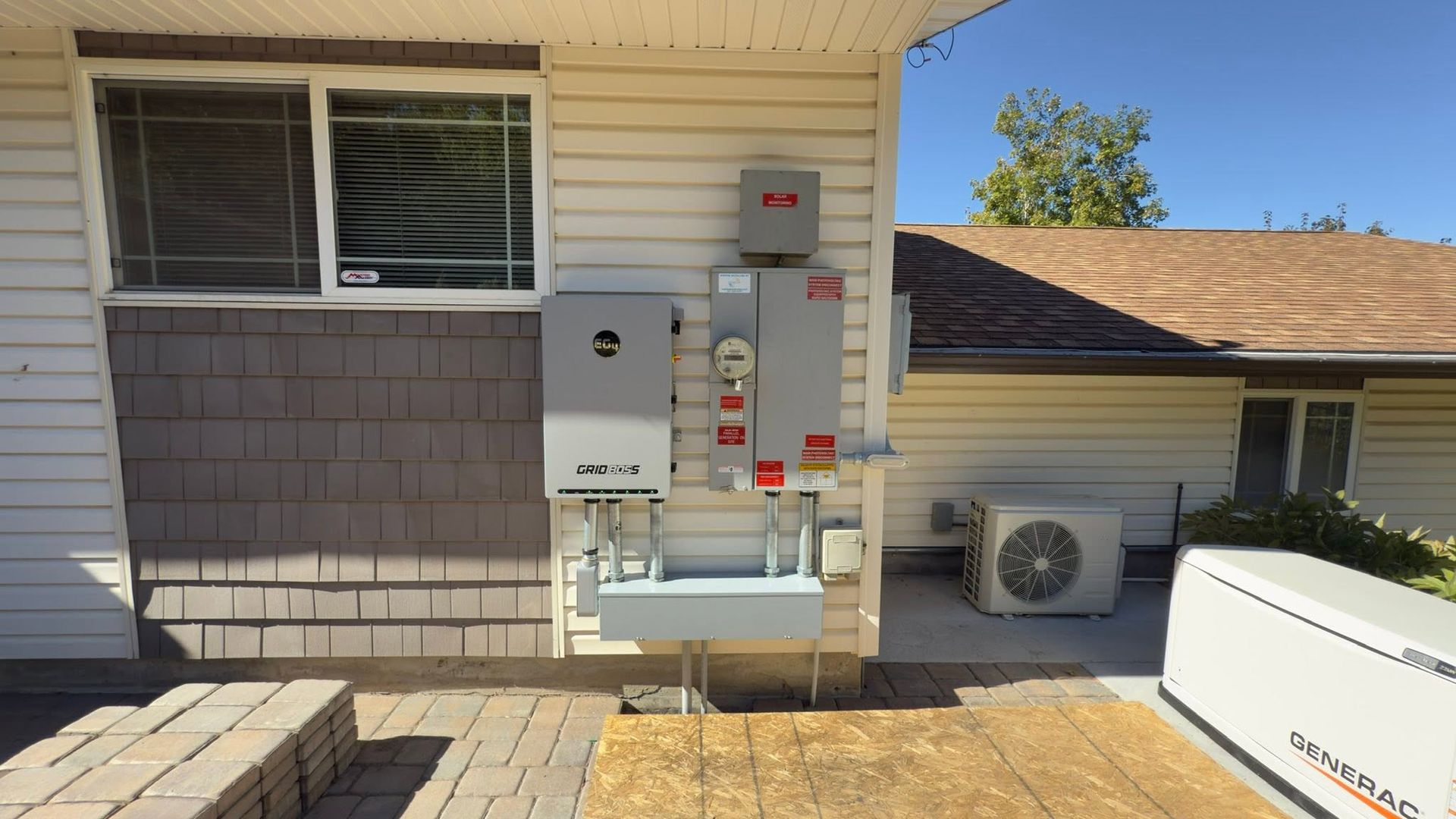 Exterior gas meters and utility equipment mounted on a house wall beside an air conditioner unit.