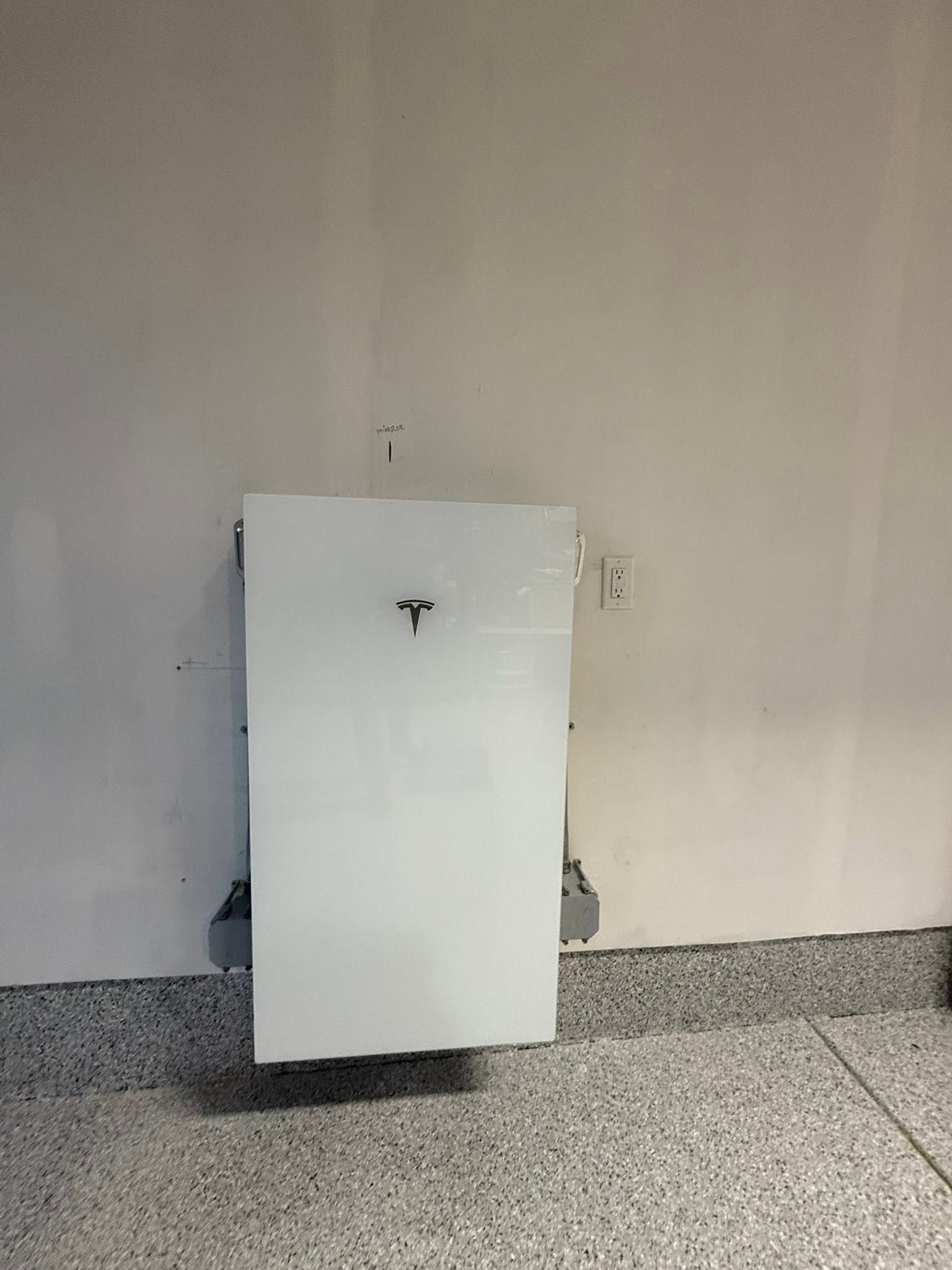 White cabinet or wall-mounted unit against a beige wall on a speckled floor