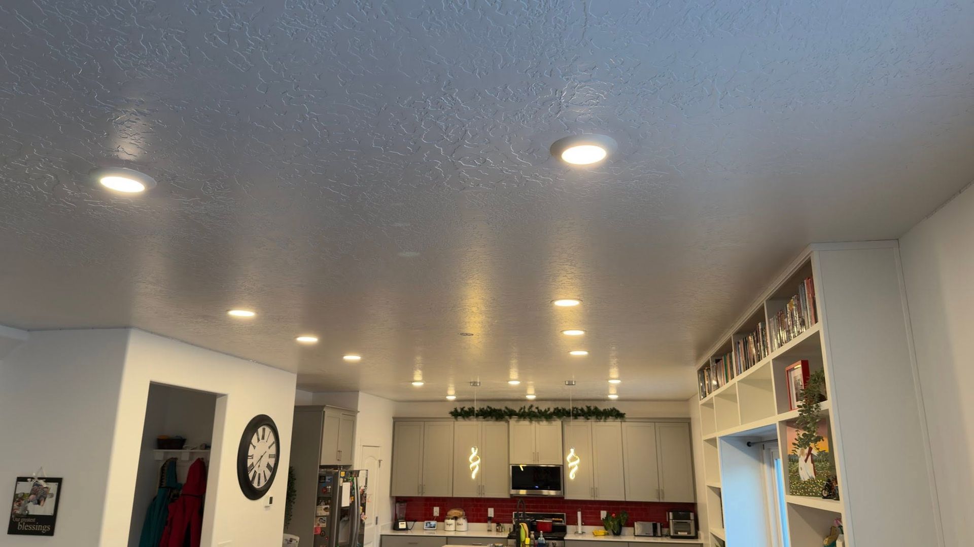 Modern kitchen and dining area with recessed ceiling lights, white cabinets, and a red backsplash.