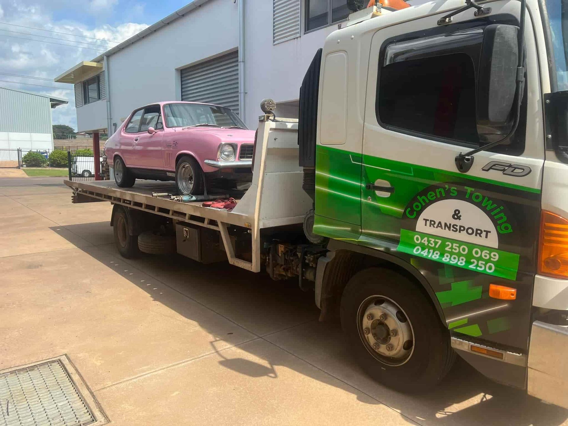A Pink Car is Being Towed by a Tow Truck — Cohen’s Towing & 4WD Recoveries In Winnellie, NT