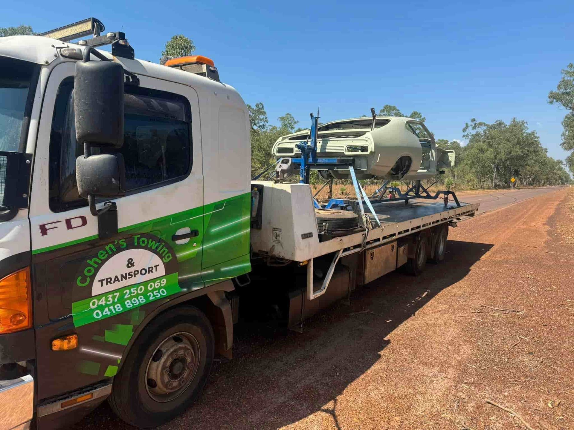 A Tow Truck With a Car on the Back is Parked on the Side of the Road — Cohen’s Towing & 4WD Recoveries In Winnellie, NT
