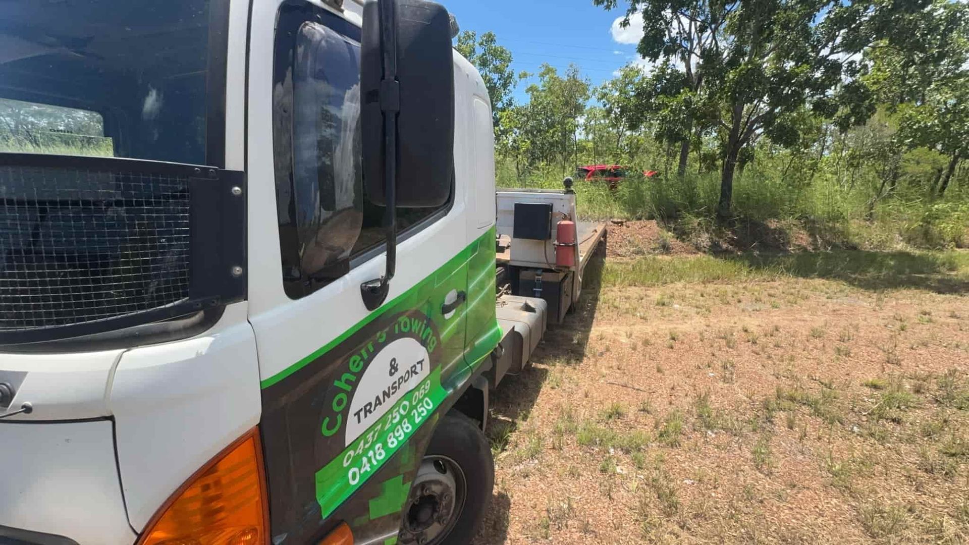 A White Truck With a Green Sticker on the Side is Parked in a Field — Cohen’s Towing & 4WD Recoveries In Winnellie, NT