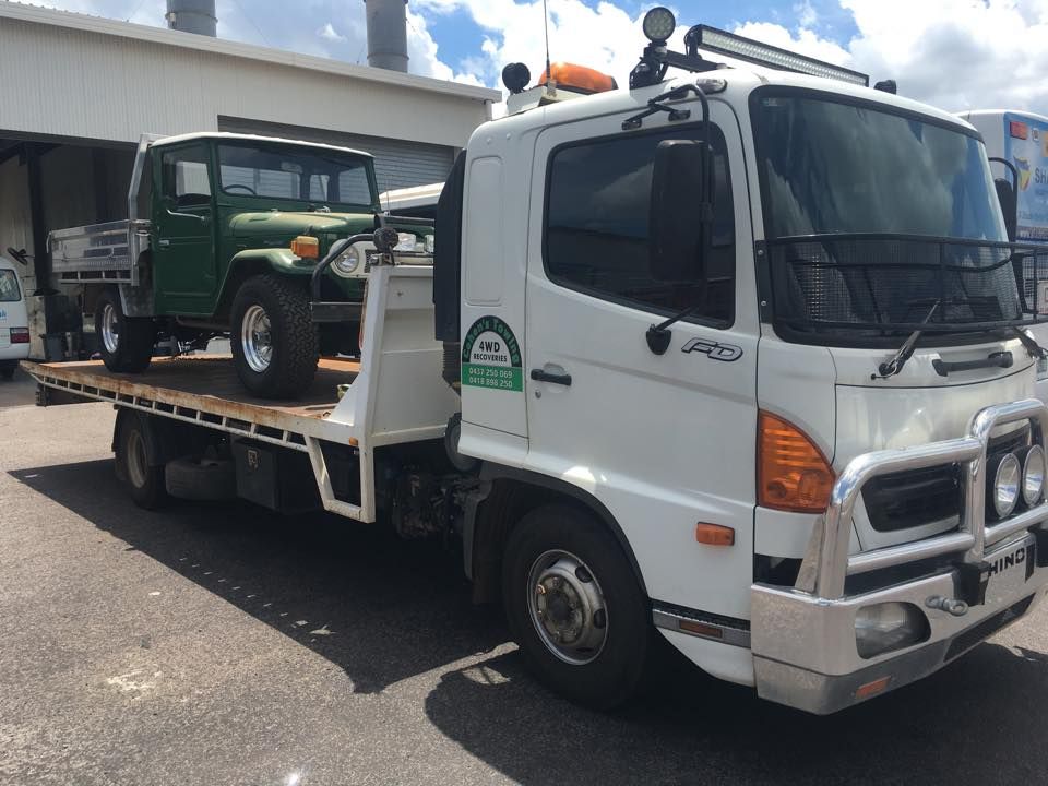 A White Tow Truck is Towing a Green Jeep — Cohen’s Towing & 4WD Recoveries In Katherine, NT