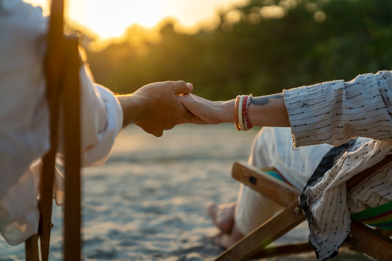 a man and a woman are holding hands on the beach .