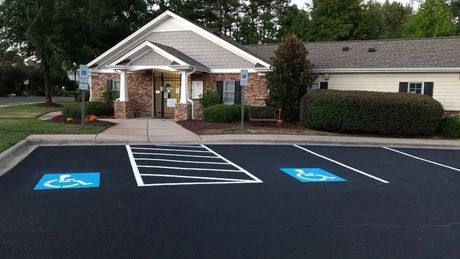 A brick and siding building with a parking lot featuring two clearly marked handicap-accessible parking spots.