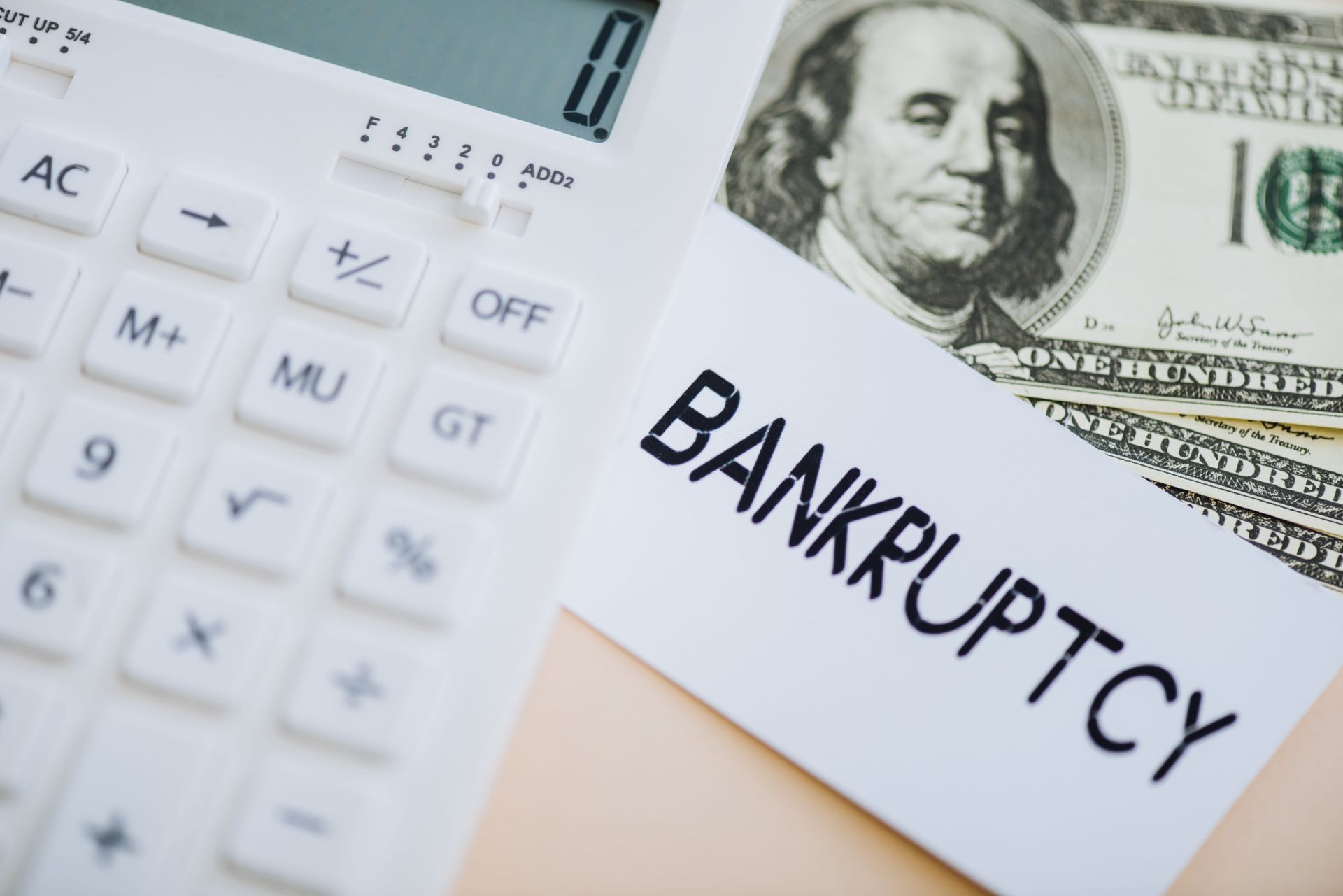 Calculator beside dollar bill and bankrupcy notice on a financial document