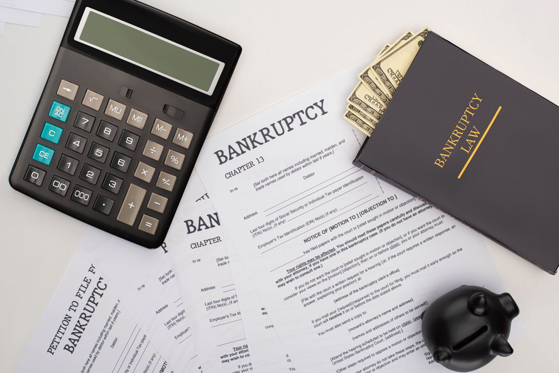 Calculator and bankruptcy paperwork on a desk beside a black gavel and notebook