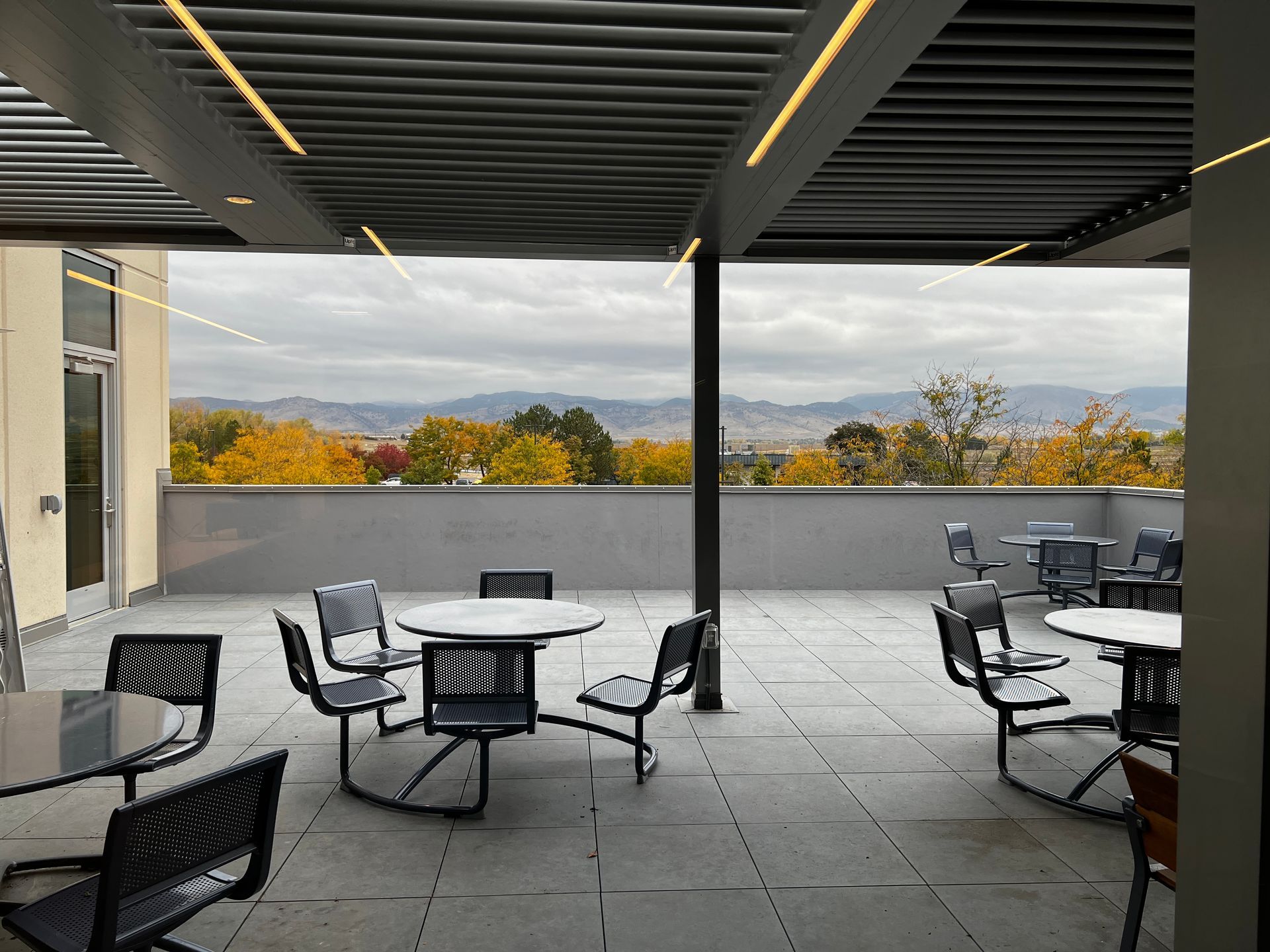 A patio with tables and chairs and a view of the mountains.