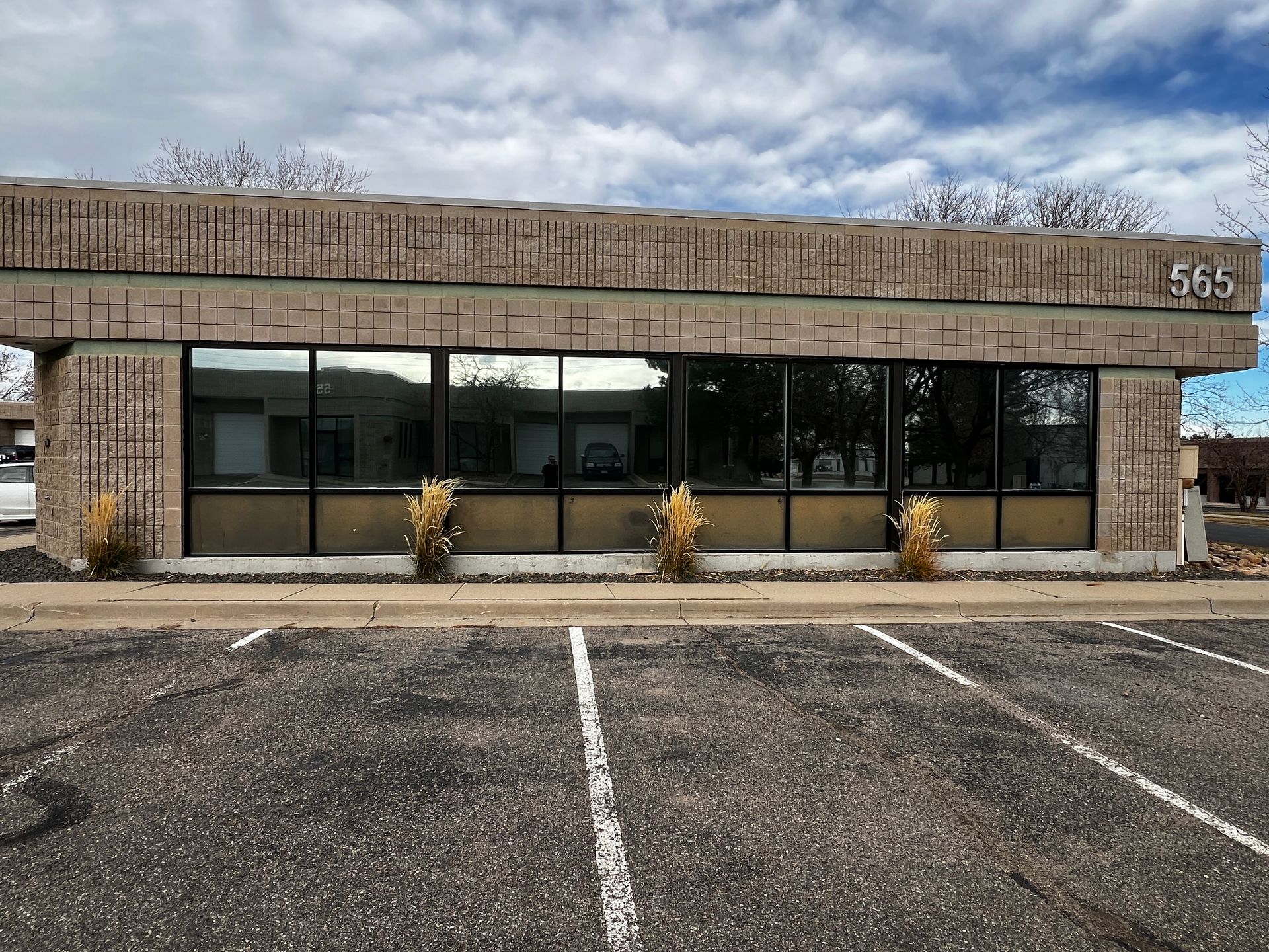 A building with a lot of windows and a parking lot in front of it.