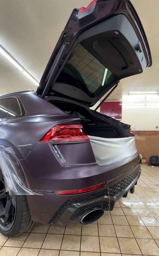 A purple car with the trunk open in a garage.
