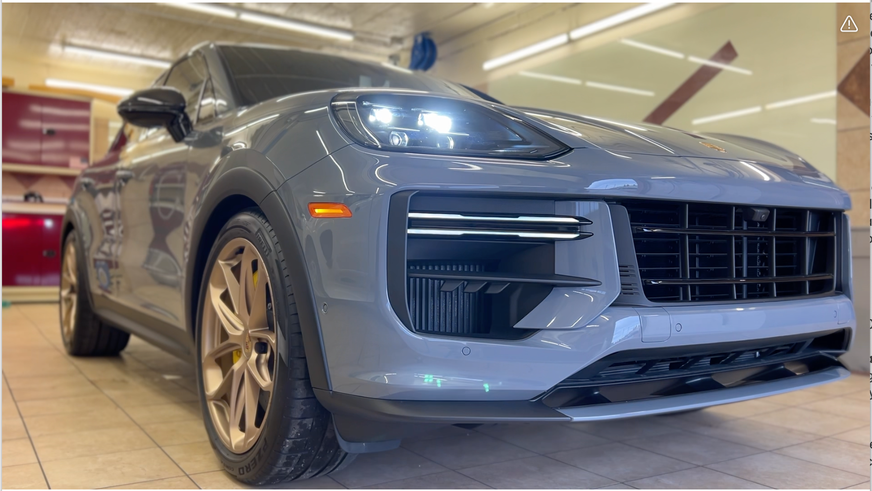A grey porsche cayenne turbo is parked in a garage.