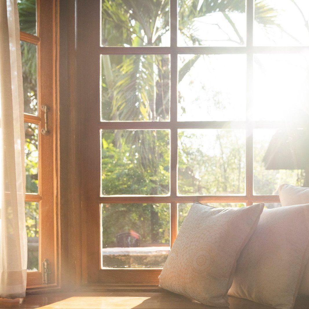 The sun is shining through the window and shining on the pillows on the window sill.