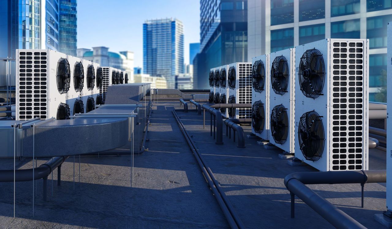 Rooftop HVAC units and ducts on a city building with glass skyscrapers in the background Rooftop HVAC units and ducts on a city building with glass skyscrapers in the background
