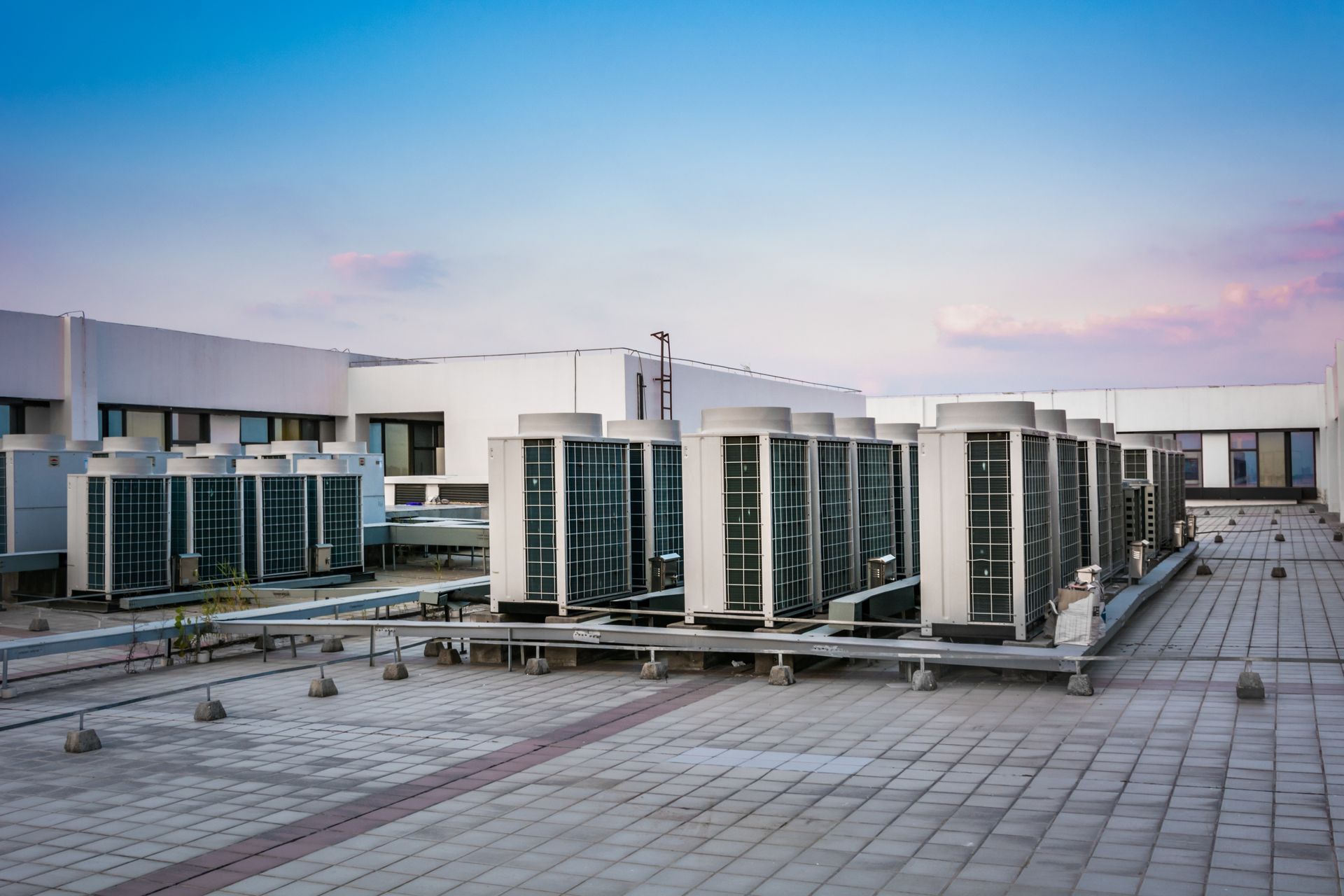 Modern airport terminal buildings with glass facades and a wide empty plaza at sunset