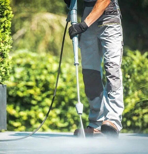 Person Wearing Work Clothes Power Washing a Gray Patio — G.N Painting and Decorating in Port Macquarie, NSW