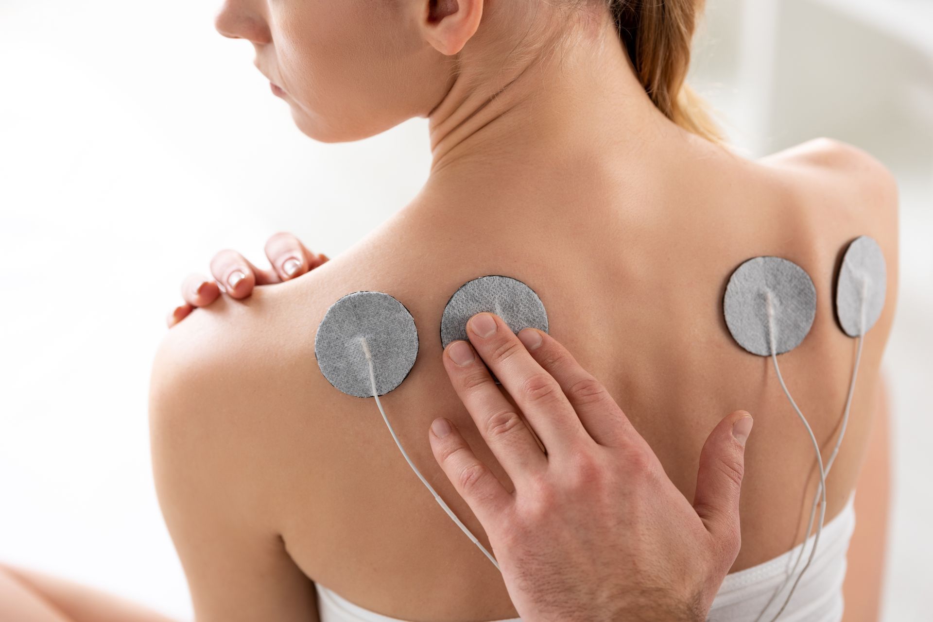 Eine Frau bekommt eine Massage mit Elektroden auf ihrem Rücken.