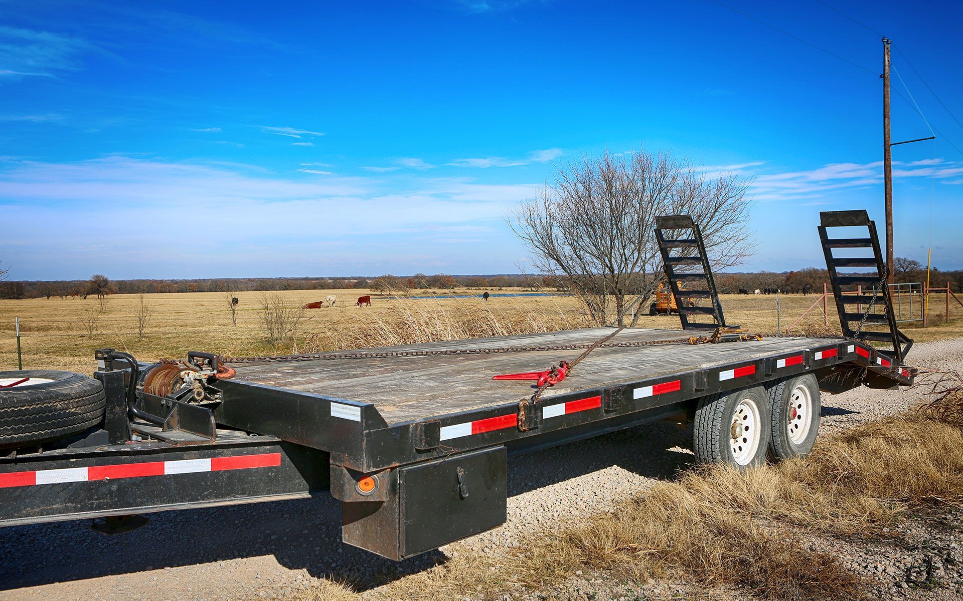 A flatbed trailer is parked on the side of a dirt road.