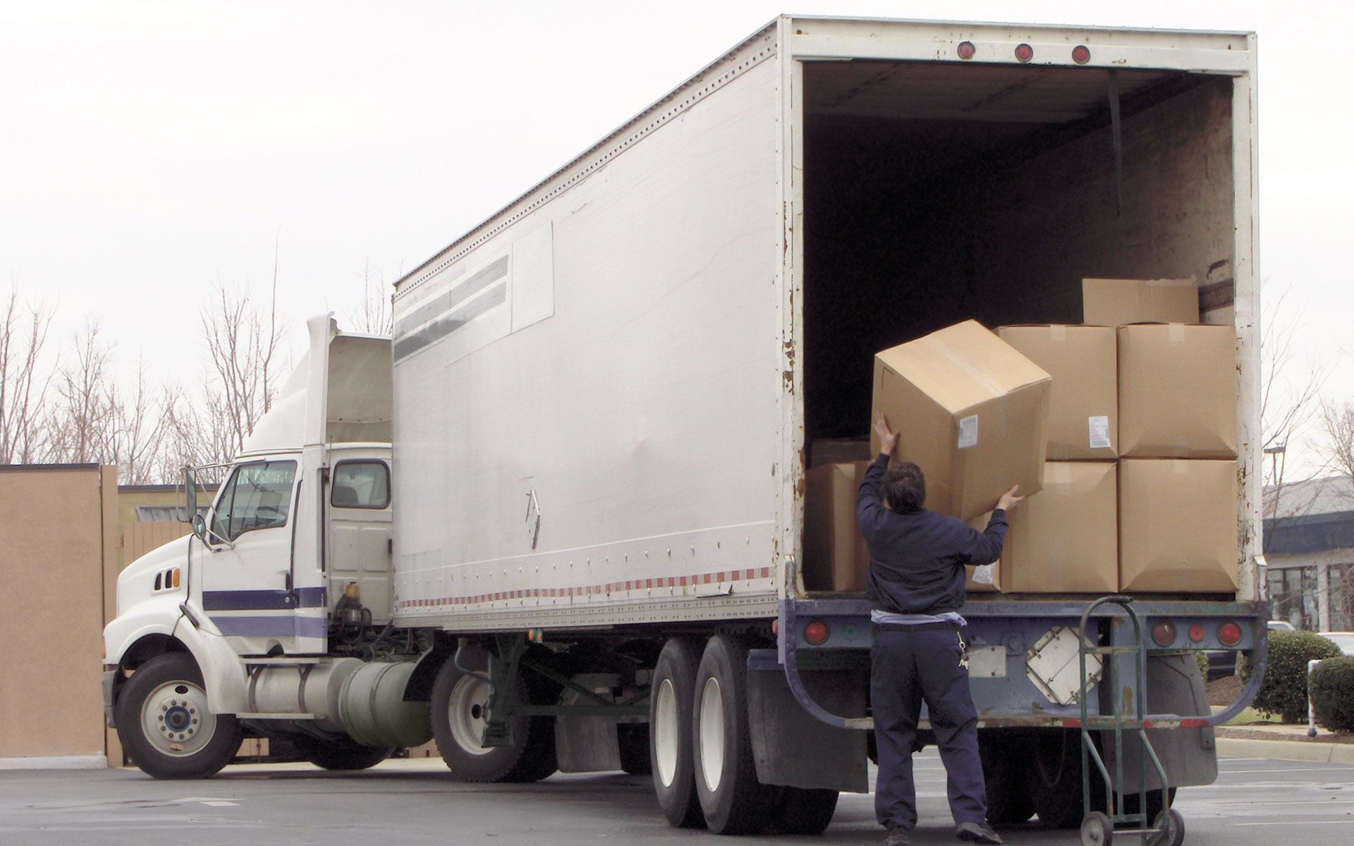 A man is loading boxes into a semi truck