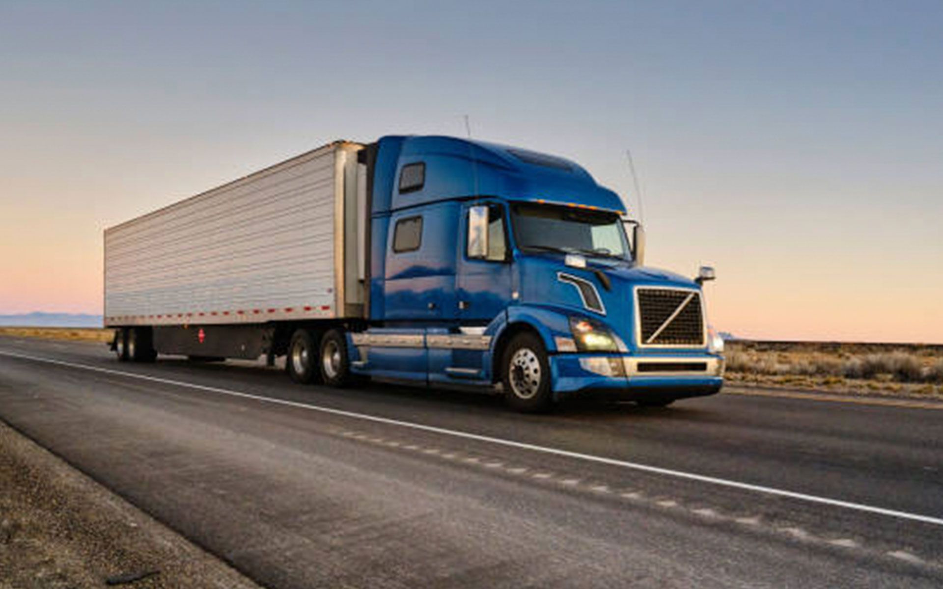 A blue semi truck is driving down a highway.