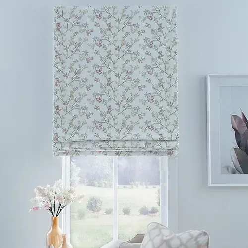 Roman shade with a floral pattern, above a window. Vase of flowers in foreground, framed artwork on the right.