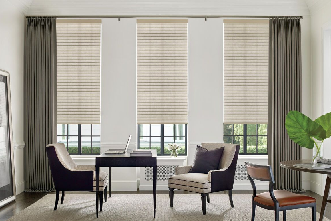Office with three windows: beige shades, grey curtains, desk, chairs, rug.