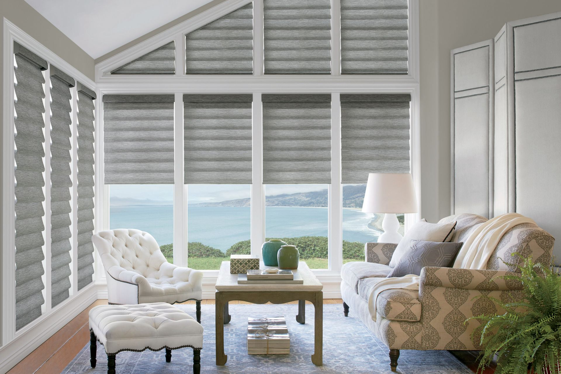 Living room with gray blinds over a window overlooking water. Furnished with seating, a coffee table, and lamp.
