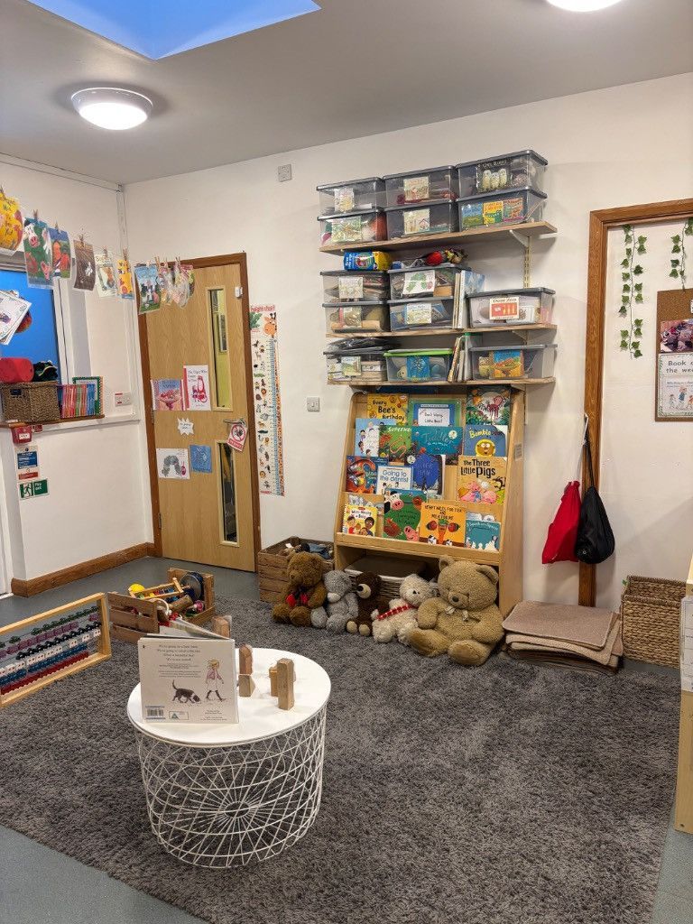 A cozy reading corner in a room. Bookshelves and a low table are set on a gray carpet.
