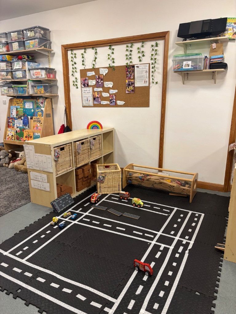 Playroom with road mat, toy cars, storage, bulletin board, and shelves of books.