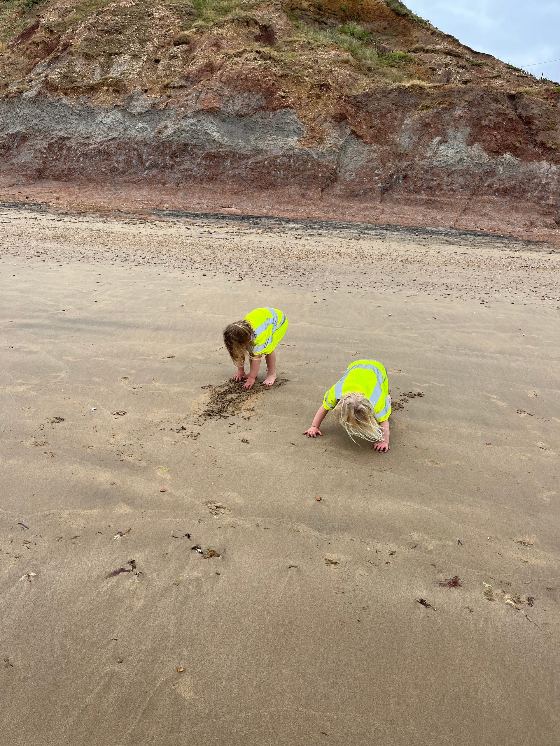 Two children are playing in the sand on a beach.