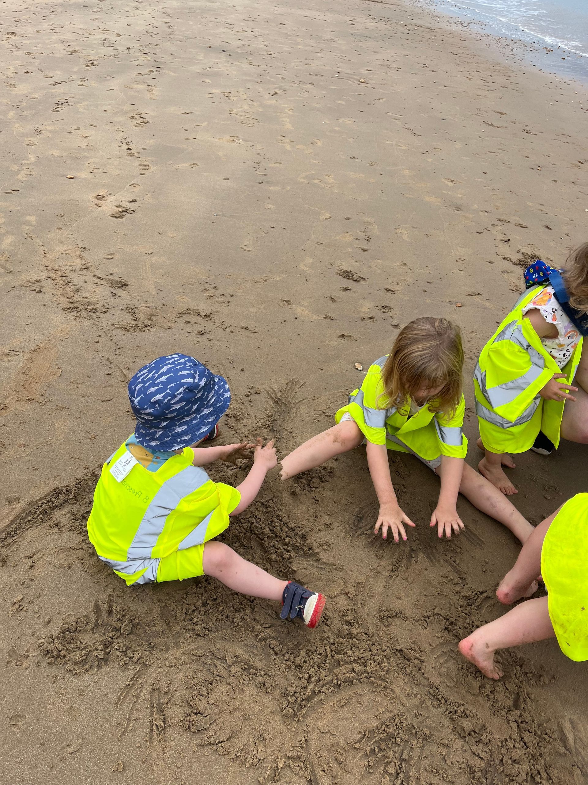 A group of children are playing in the sand on the beach.